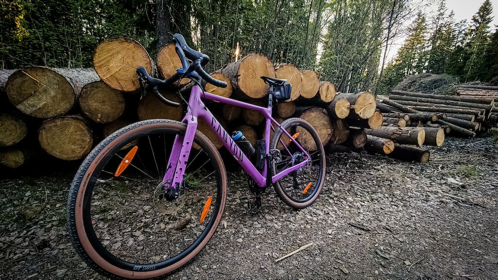 rower gravelowy oparty o stos kłód drzew